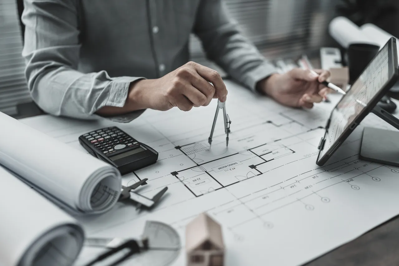 Praca nad projektem budowlanym z użyciem cyrkla i planów architektonicznych